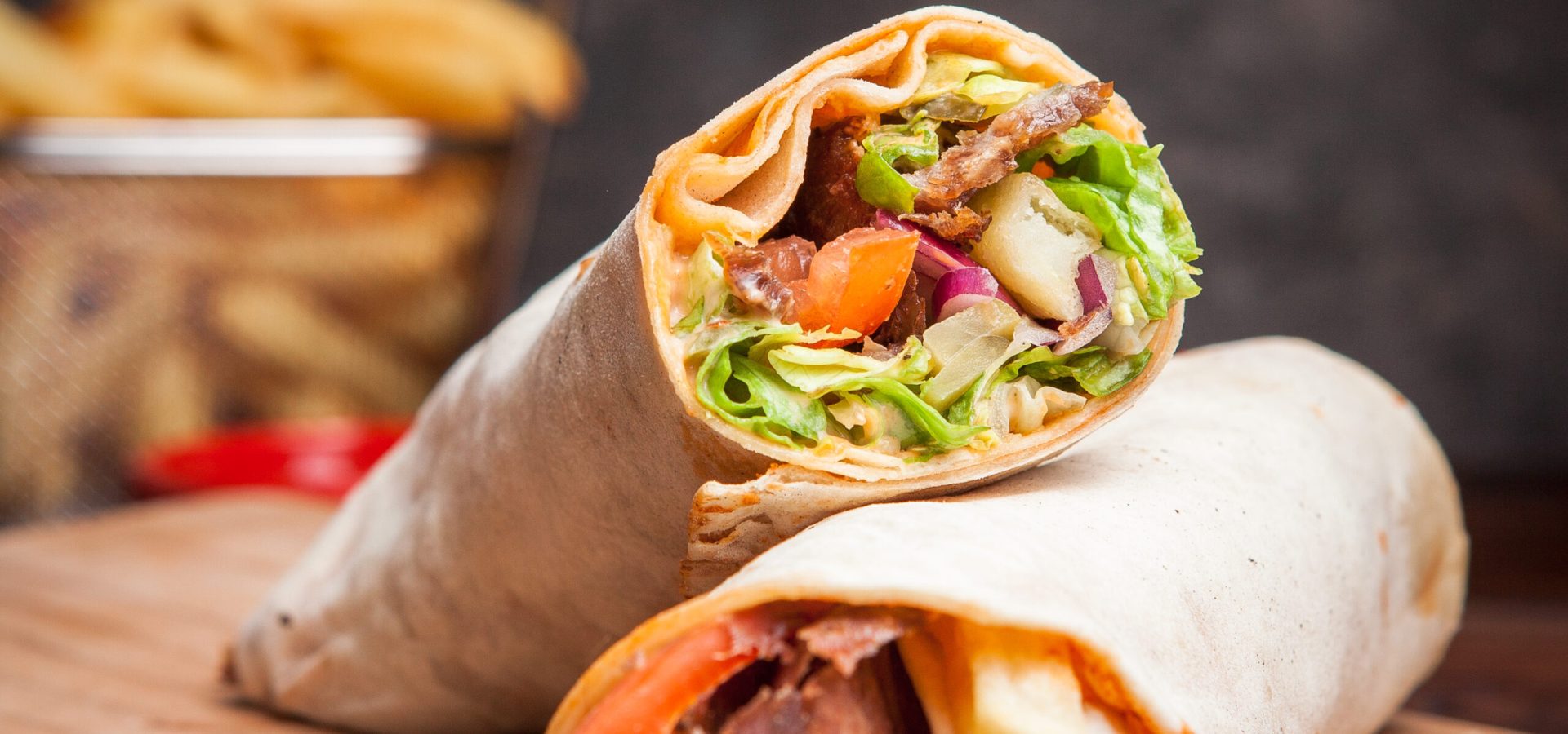 Side view shawarma with fried potatoes in board cookware on stone background